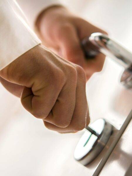 A man closing a door and turning a key in the lock